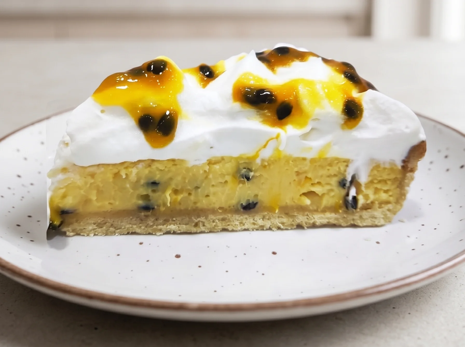 Porción o tarta de mousse de maracuyá con cobertura brillante amarilla de semillas